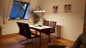 Een eetruimte met een tafel, stoelen en een hangplant.