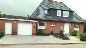 Een herenhuis met garage, een kleine tuin en een gevel van baksteen.