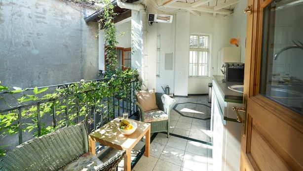 A balcony with wicker furniture, a table with fruit, and a kitchen area with a sink and cabinets. - Luxury Penthouse in the ❤️ Of Vienna (Leopoldstadt)