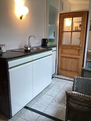 A compact kitchen with a sink, a coffee maker, and a cabinet.