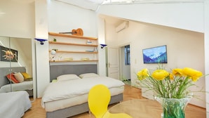 A modern bedroom with a bed, a chair, a TV, and a vase with flowers. - Luxury Penthouse in the ❤️ Of Vienna (Leopoldstadt)