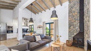Una sala de estar moderna con un sofá, una mesa redonda, una chimenea y una cocina al fondo.