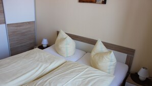 Cama bem arrumada com duas almofadas e mesa de cabeceira com abajur.