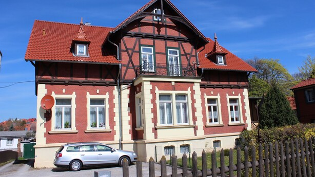 Um edifício de dois andares com telhado de telhas vermelhas e uma varanda.