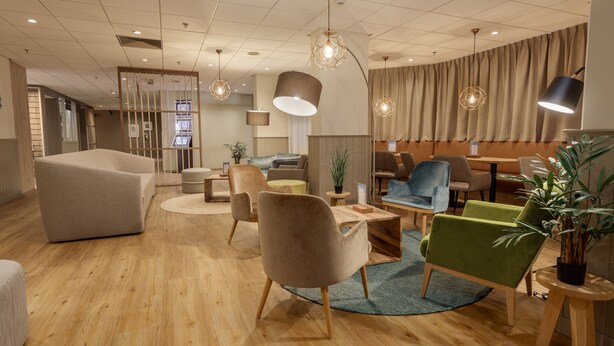 A modern lounge area with wooden flooring, comfortable seating, and pendant lighting. - Beach Hotel Zandvoort BY Center Parcs (Zandvoort)