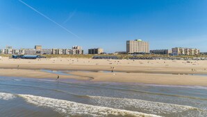 A beach with a sandy shore and a few buildings in the background.