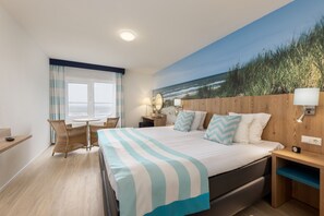 Relax in this serene beachfront room with a large bed, wooden headboard, and ocean views.