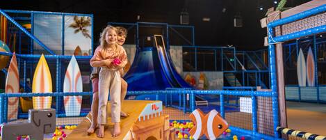 An indoor play area with a slide, climbing structures, and a ball pit.