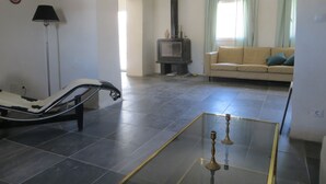 A living room with a sofa, a glass coffee table, a chair, a lamp, and a fireplace.