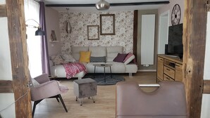 A living room with a sofa, armchairs, a coffee table, and a TV stand. - Apartment Rose       (Obermöllrich)
