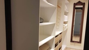 A hallway with a wooden floor, white shelving units, and a mirror on the right. - Apartment Rose       (Obermöllrich)