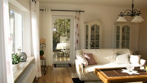 A cozy living room with a white sofa, a wooden coffee table, and a view of the outdoors through a glass door. - Holiday house on the outskirts of Klagenfurt with a wonderful view (Klagenfurt am Wörthersee)