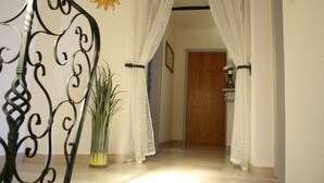 A hallway with a staircase, white curtains, a potted plant, and a wooden door. - Holiday house on the outskirts of Klagenfurt with a wonderful view (Klagenfurt am Wörthersee)