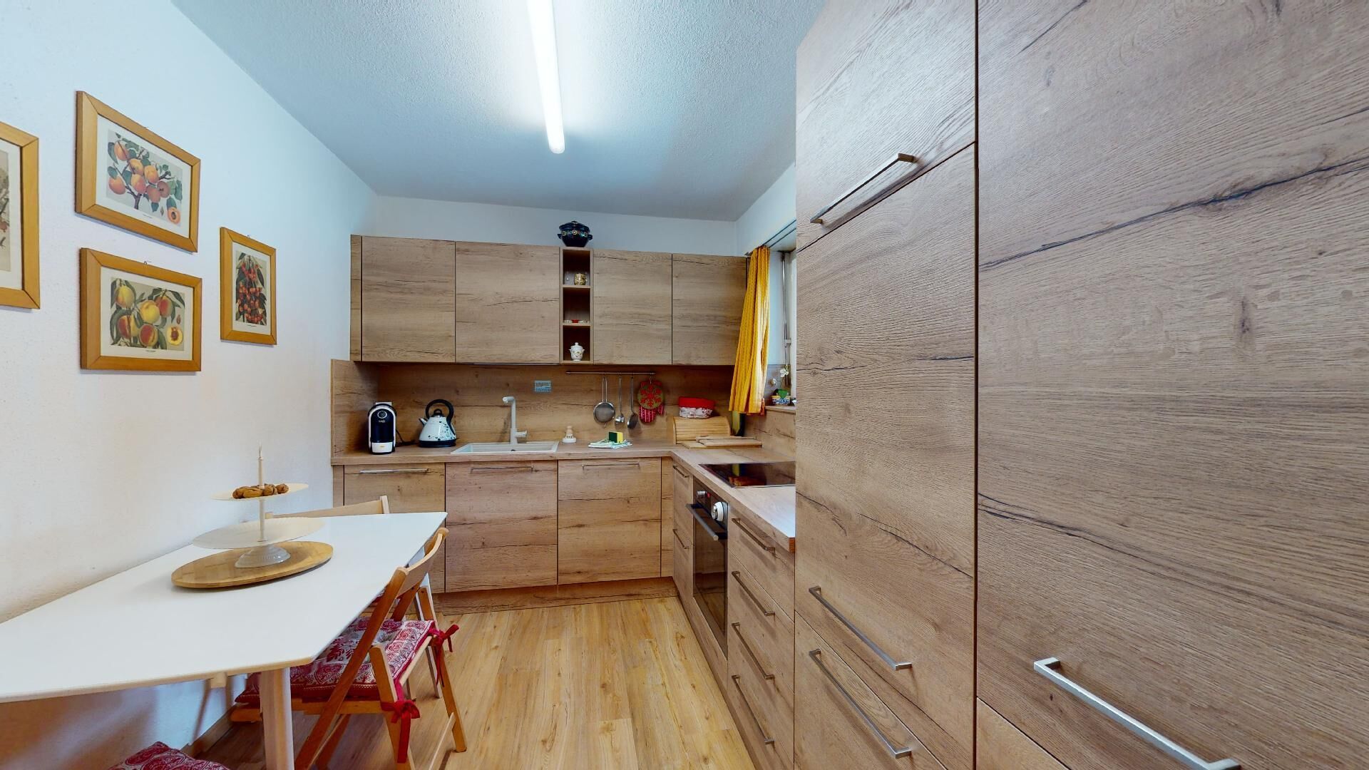 A compact kitchen with wooden cabinets, a white countertop, and a dining area with a table and chairs.