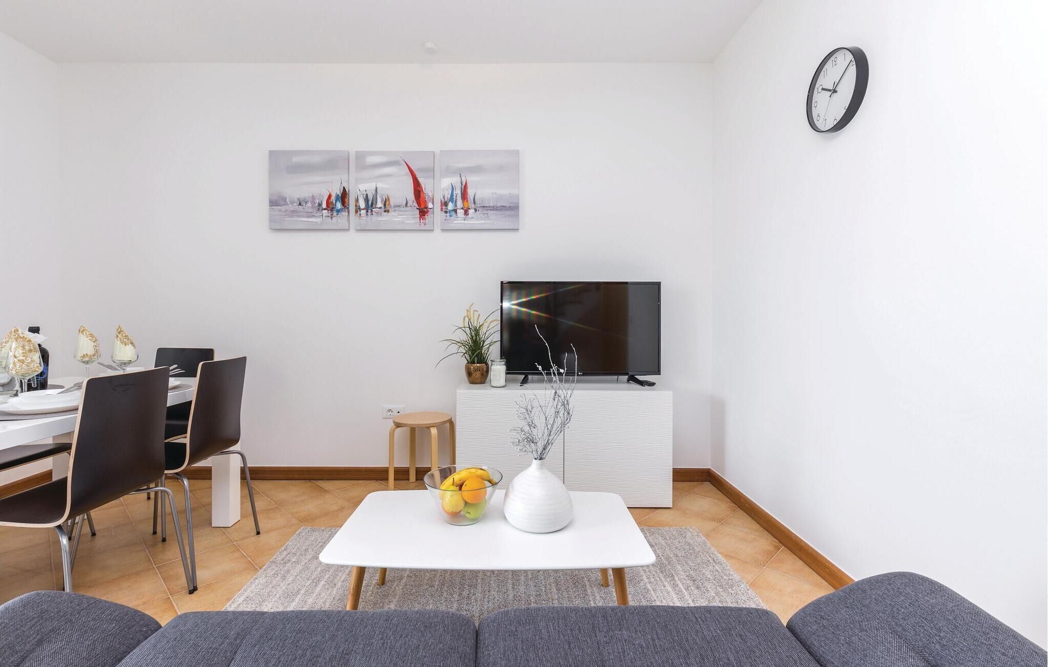 Ein modernes Wohnzimmer mit Essbereich, einem Flachbildfernseher und einer Wanduhr.