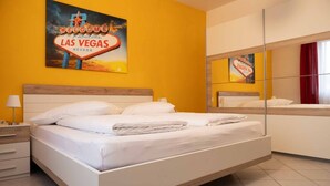Habitació d'hotel amb llit, una tauleta de nit, una làmpada, un mirall i una paret amb un rètol de Las Vegas.