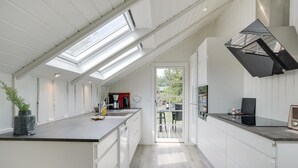A modern kitchen with skylights, white cabinetry, and a central island. - Beach front home in Blåvand with sauna (Blåvand)
