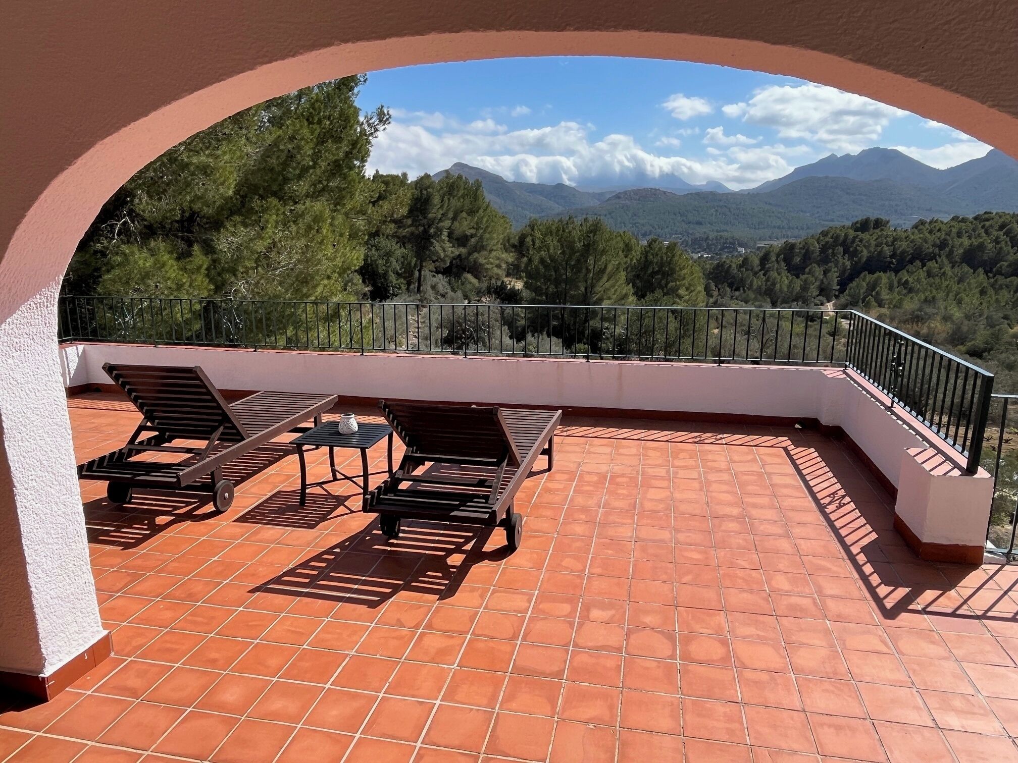Une terrasse offrant une vue sur les montagnes, aménagée avec des chaises longues et une table.