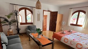 A hotel room with a bed, a sofa, a table, a potted plant, and a view of the outdoors. - Casa Ensueño - an oasis of peace with fantastic views. (Jalón)