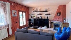 A living room with a grey sofa, blue armchairs, a fireplace, and a TV. - Casa Ensueño - an oasis of peace with fantastic views. (Jalón)
