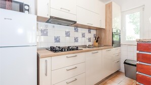 Une cuisine moderne avec des meubles blancs, une cuisinière à gaz et un four encastré.