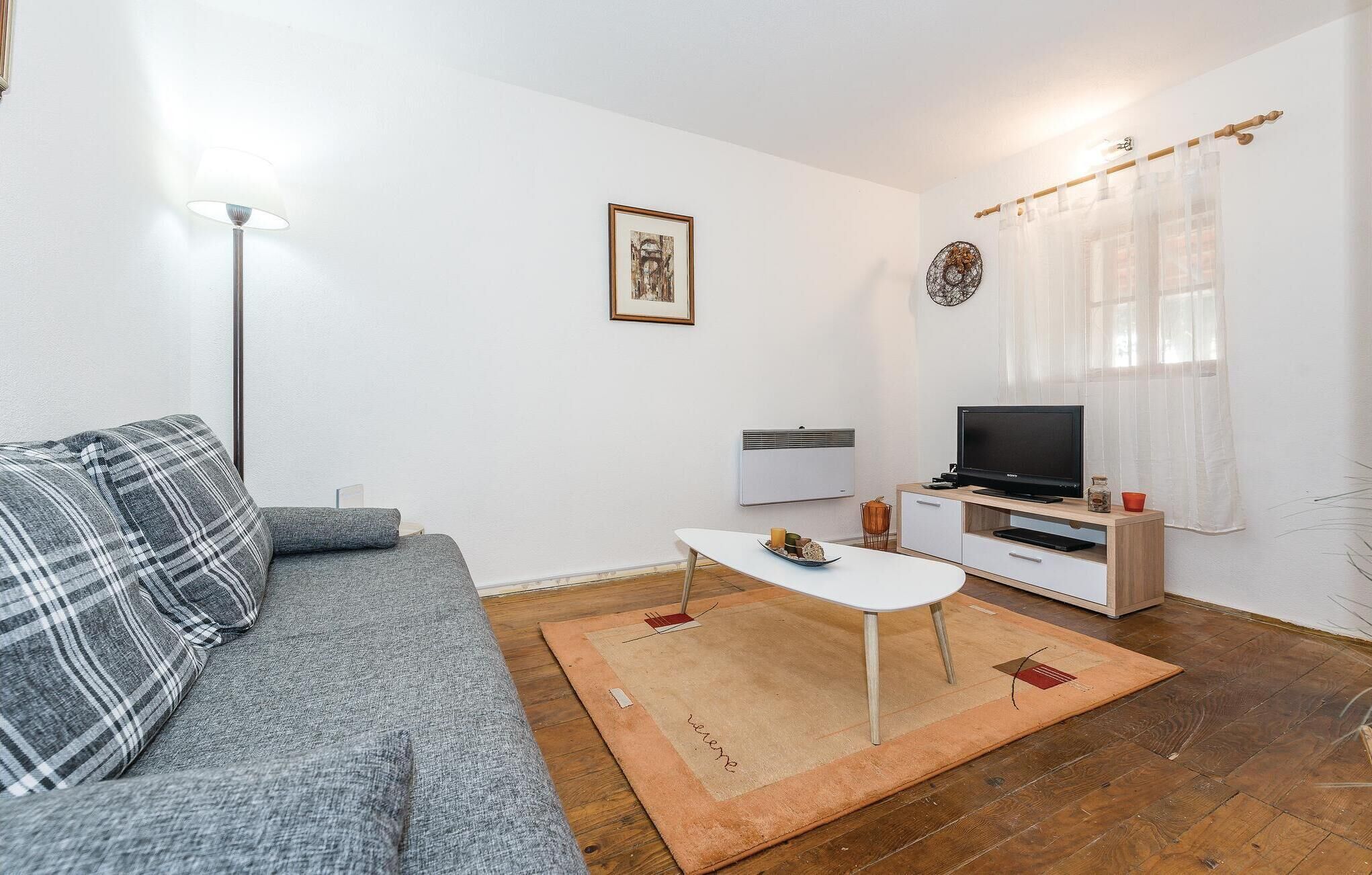 A living room with a sofa, coffee table, TV, and a radiator.
