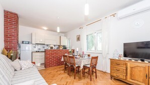Un salon confortable avec un canapé, une table à manger et des chaises, un téléviseur et un meuble en bois.