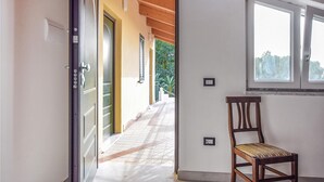 A hallway with a wooden door, a chair, and a window.