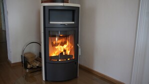A modern wood-burning stove with a glass front, a control panel, and a chimney. - Holiday in the castle park Hohen Niendorf with terrace & view to the Baltic Sea (Hohen Niendorf)