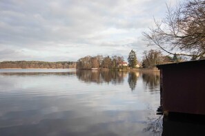Un lac paisible où se reflètent les arbres et un bâtiment situé sur la droite.