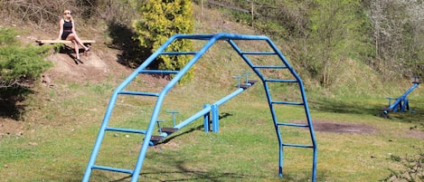 Un parque infantil con una estructura azul para escalar y un banco de madera.
