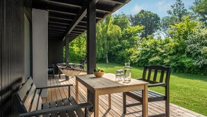 Eine Holzterrasse mit Tisch, Stühlen, einer Hängematte und einer Obstschale.