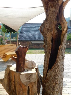 A tree trunk with a hollow, a wooden sculpture, and a bench.