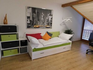 Un dormitorio con una cama, un cartel con un panorama urbano, una planta y un escritorio con cajones.