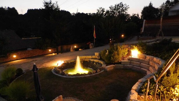 A landscaped garden with a central water feature, stone seating, and a flagpole. - Trudis Apartment - Apartment 5 ***** (DG) (Veringenstadt)