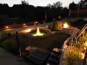 Un jardín ajardinado con una fuente central, asientos de piedra e izado de bandera.