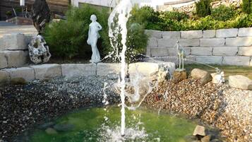 Ein Garten mit einem Wasserspiel, einschließlich eines Brunnens und einer Statue.