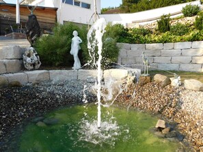 A garden with a water feature, including a fountain and a statue.