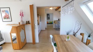 A modern interior with a wooden dining table, green chairs, a kitchen in the background, and a staircase leading to another level. - Trudis Apartment - Apartment 5 ***** (DG) (Veringenstadt)