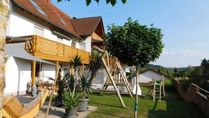 A house with a wooden balcony, a hammock, and potted plants. - Trudis Apartment - Apartment 5 ***** (DG) (Veringenstadt)