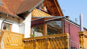 A two-story house with a red-tiled roof, a balcony with yellow railings, and a large window. - Trudis Apartment - Apartment 5 ***** (DG) (Veringenstadt)
