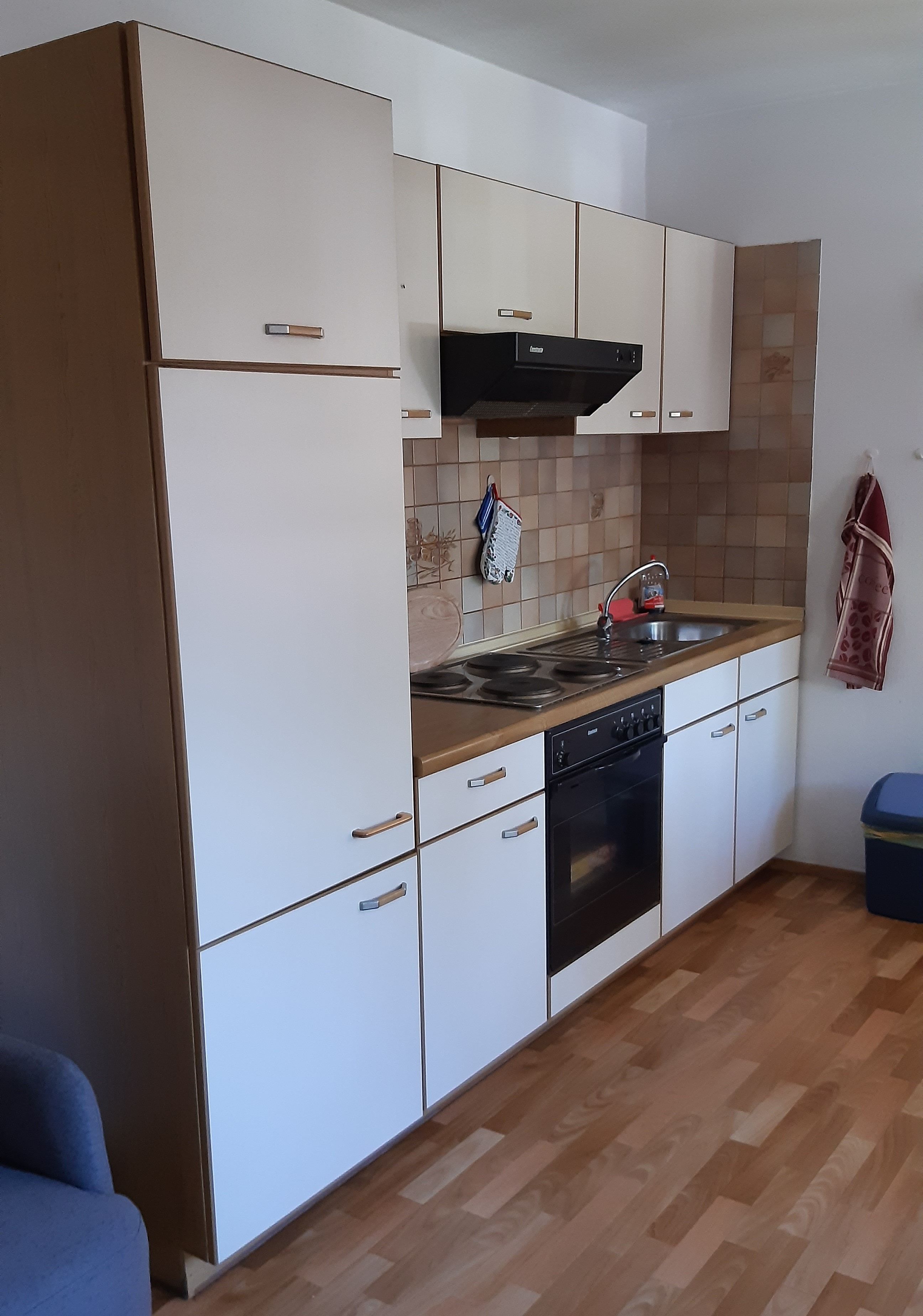 A kitchen with white cabinets, a black stove, a sink, and a wooden countertop.