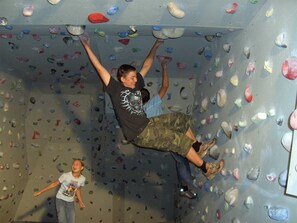 Eine Person erklimmt eine Wand mit unterschiedlich geformten Griffen.