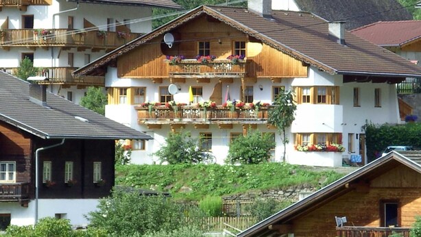 A traditional chalet-style building with wooden balconies, a central balcony with flower boxes, and a white tower structure. - Fallwindes 1 - Gratzhof - Kals (Lesach)