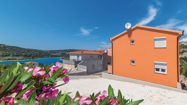 Un edificio costero con antena parabólica, un balcón y vistas al mar.