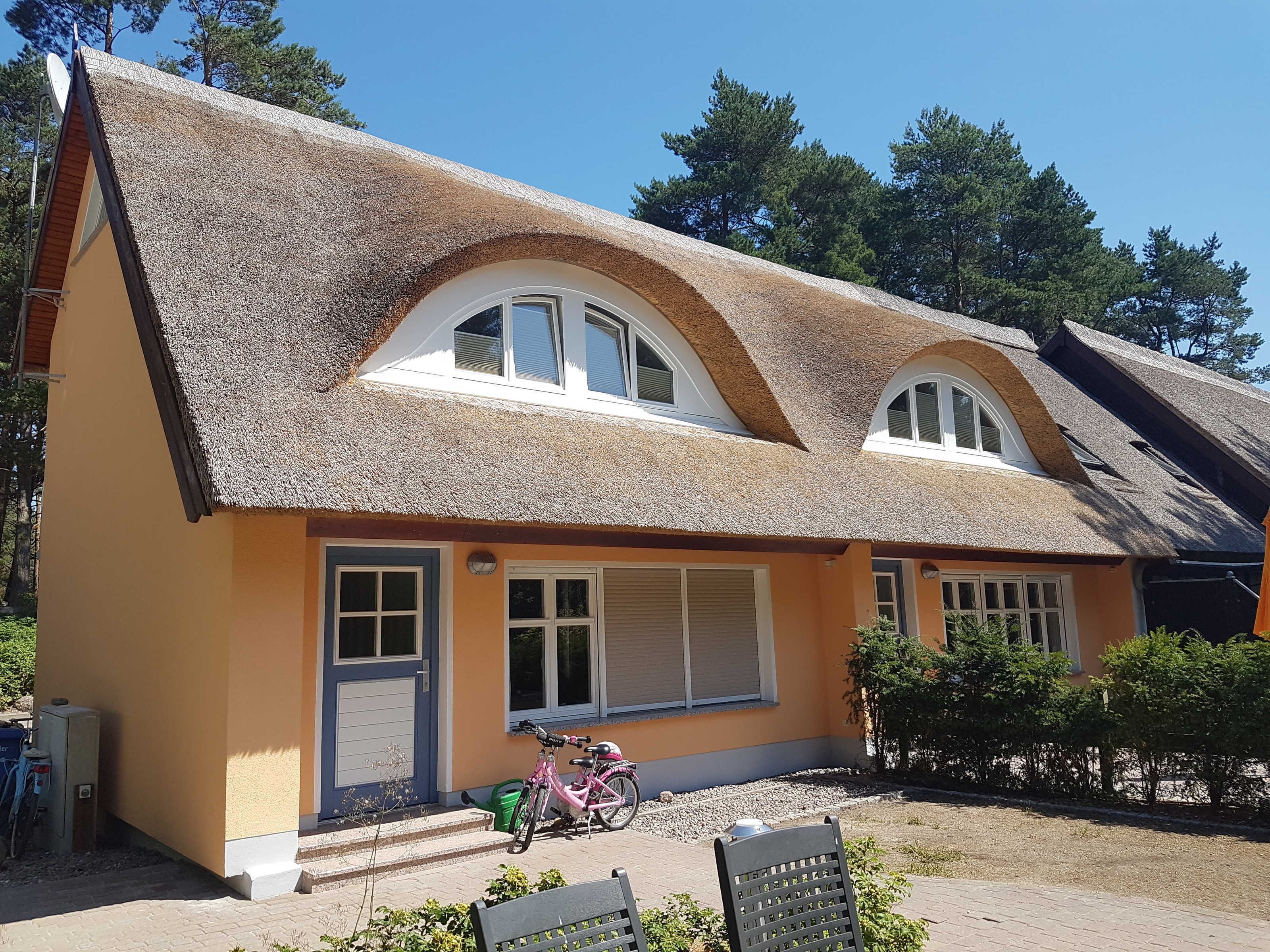 Ein Haus mit Strohdach, einer Veranda und einem Fahrrad davor.