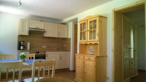 A compact kitchen with wooden cabinets, a coffee maker, and a dining area with a table and chairs.