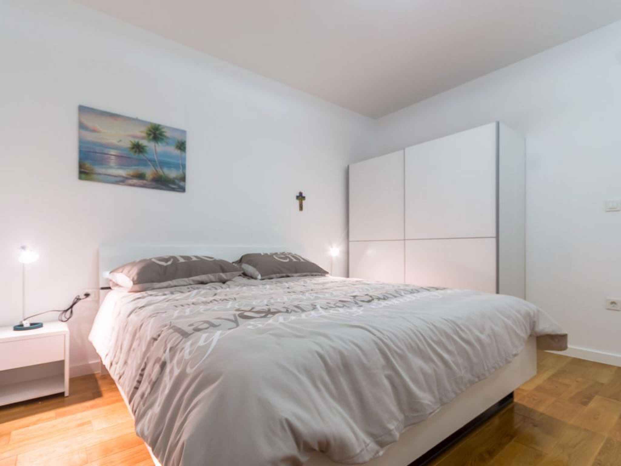 Quarto com cama, mesa de cabeceira e guarda-roupa.