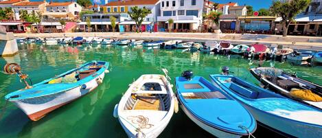 A marina with several boats docked, a clear blue sky, and buildings in the background.