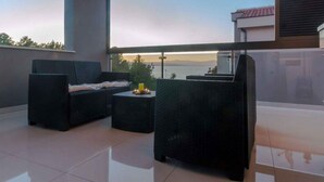 A balcony with a view of the sea, featuring two wicker sofas and a small table with a candle. - Holiday apartment 150 m from the beach (Njivice)